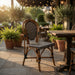 Wood outdoor side chair with woven black seat and cream lattice back panel.